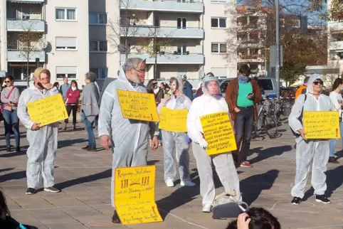 Mit Schutzanzügen und mit Plakaten: Teil der Demonstranten auf dem Berliner Platz.