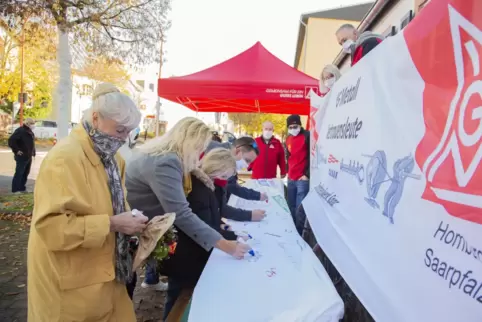 Vor dem Wasgau-Markt in Limbach setzen Bürger ihre Unterschriften unter ein Banner der IG Metall, auf dem gegen Stellenstreichun