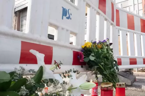 Blumen und Kerzen vor dem ausgebrannten Haus in der Winzler Straße