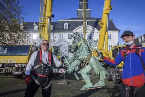 Die beiden Dachdecker Werner Schwaben und Timo Frey (von links) montieren den Löwen wieder auf der Turmspitze.