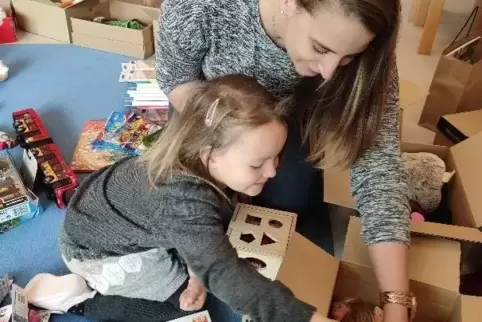 Paula mit Erzieherin Jennifer Götz beim Packen eines Päckchens .