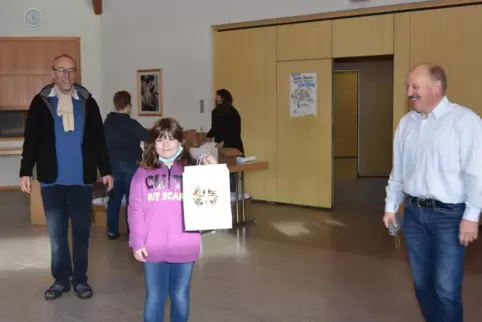 Sophia Stobbe freut sich mit Pfarrer Michael Hergl (links) und Hans Beck (rechts) über die erste fertiggepackte Advents-Familien