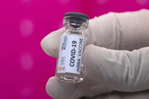 Ein Labortechniker hält einen Glasbehälter eines sich in der Entwicklung befindlichen, möglichen Covid-19-Impfstoffs in der Hand