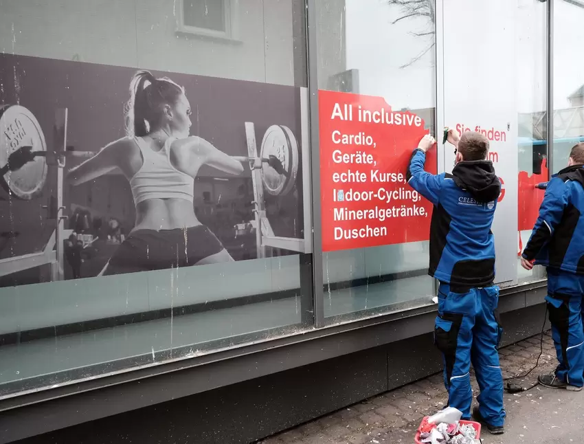 Mitarbeiter einer Reinigungsfirma entfernen die alten Klebefolien.