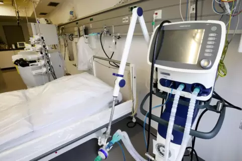 Ein Beatmungsgerät steht in einem Krankenhaus neben einem Intensivbett. 