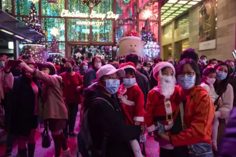 Menschen posieren an Heiligabend in Hongkong vor Weihnachtsdekorationen.