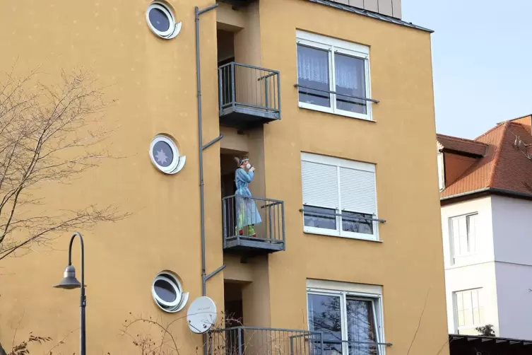 Eine Mitarbeiterin des Edenkobener Heims in Schutzmontur auf einem Balkon. 