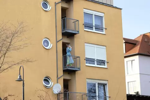 Eine Mitarbeiterin des Edenkobener Heims in Schutzmontur auf einem Balkon. 