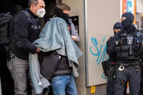 Ein Mann wird bei der Razzia in Berlin abgeführt.