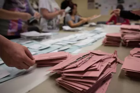 Wahlhelfer sortieren in einem Briefwahllokal die roten Wahlbriefe.
