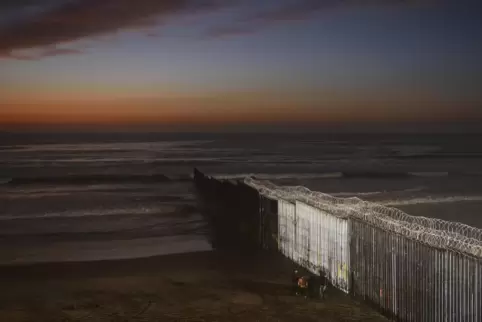 Menschen stehen an der Grenzmauer zwischen Mexiko und San Diego, Kalifornien. US-Präsident Biden stoppte den Mauerbau. 