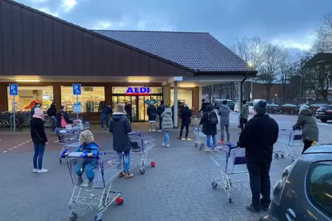 Zahlreiche Kunden warten am Samstagmorgen vor einer Hamburger Aldi-Filiale.