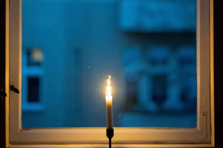 Eine Kerze brennt in einem Fenster als Zeichen des Gedenkens an die Corona-Toten.