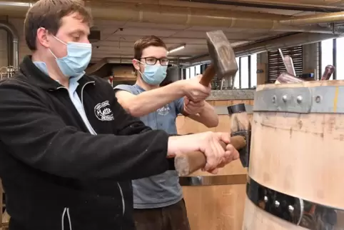 Ralf Mattern (links) und sein Mitarbeiter Philipp Janson bereifen ein 2500-Liter-Holzfass. Sie haben es aus Pfälzer Eiche herges