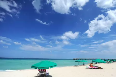 Urlaubsgäste liegen am Strand vor der Küste Floridas. Unter der Oberfläche fließt der Golfstrom und transportiert das Wasser bis