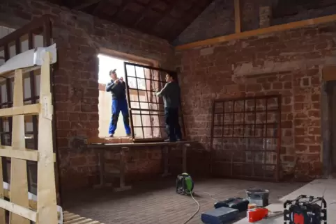 Die beiden Gemeindearbeiter Toni (links) und Christian Heimsott bauen die alten Sprossenfenster wieder ein.