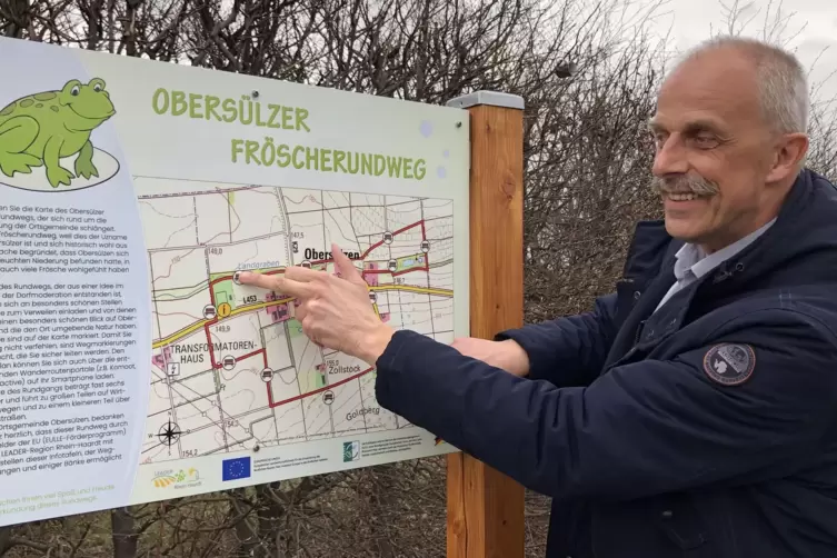 Ortsbürgermeister Andreas Lehmann erläutert den fast fertigen Frösche-Rundweg anhand einer Hinweistafel, die am Parkplatz des SV