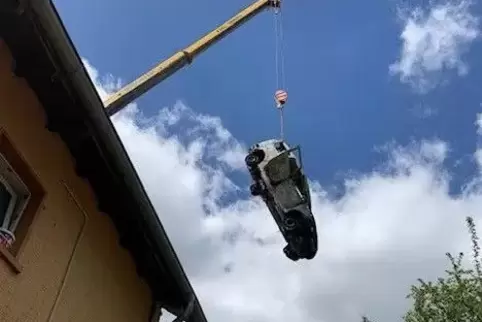 Der ausgebrannte Dacia musste mit einem Kran aus dem Garten hinterm Haus auf die Straße gehievt werden. 