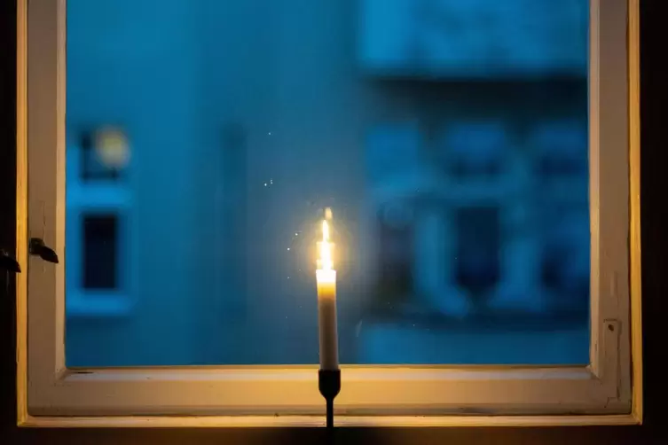 Eine Kerze brennt in einem Fenster als Zeichen des gemeinsamen Gedenkens im Rahmen der Aktion "#lichtfenster" für die Toten im Z