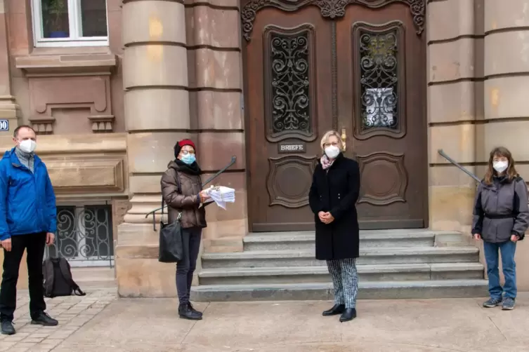 Ein dicker Stapel Unterschriften mit Olivenzweig unter der Schleife: Angelika Keßler übergibt das Paket vor dem Stadthaus an OB 