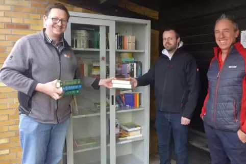 Bücherpate Patrick Sema und Bürgermeister Andreas Schneider räumten den neuen Bücherschrank ein, den Matthias Bossert gebracht h