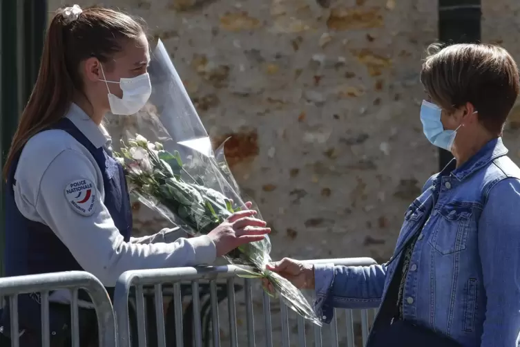 Die Betroffenheit in Frankreich ist groß: Eine Frau überreicht einer Polizeibeamtin Blumen vor einer Polizeistation.