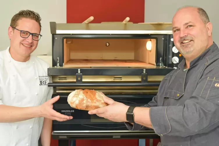 Markus Pape (links) und Bäcker Tommy Weinz mit einem Meisenheimer-Hof-Brot aus den neuen Öfen in der neuen Küche. 