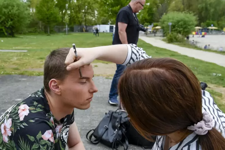 Maskenbildnerin Laura Willing bereitet Model Marcin Jacob Curanski auf das Fotoshooting vor. 