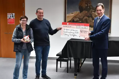 Georg Lixenfeld, Mitglied des Vorstands der Sparkasse Rhein-Haardt, überreicht dem Ehepaar Baßler einen symbolischen Scheck.