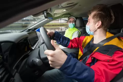 Fahrlehrer Rouven Klein und sein Fahrschüler Adrian Bredebusch (vorn) sitzen in einem wasserstoffbetriebenen Fahrschulauto. 