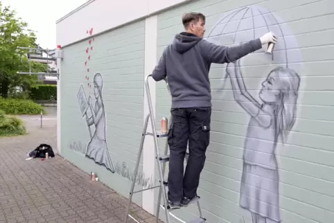 Poetische Motive: Rick Riojas bei der Arbeit an Gabriela Hilfs Mauer am Dannstadter Marktplatz. 