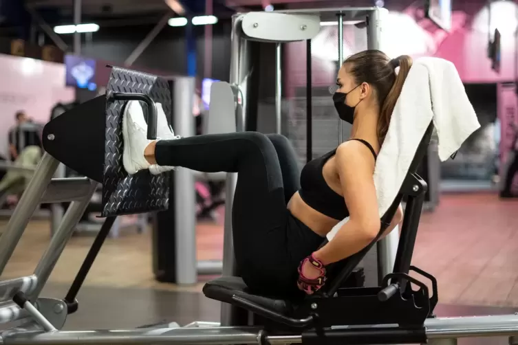Eine Frau trainiert in einem Studio an einer Beinpresse. Fitnessstudios haben noch lange mit Coronafolgen zu kämpfen.