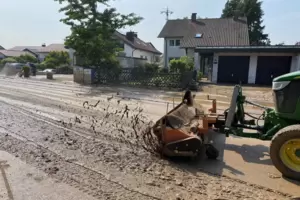Aufräumarbeiten am Mittwochvormittag: Ein Traktor schiebt den Schlamm von der Straße zu einem Lastwagen, in den er aufgeladen wi