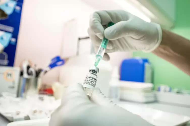 Ein Arzt zieht eine Spritze mit Impfstoff auf. 