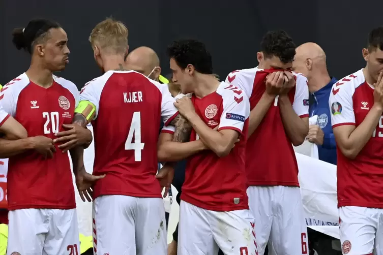 Dänische Spieler reagieren als sie um ihren Mannschaftskameraden Christian Eriksen, der von Sanitätern während des Spiels versor