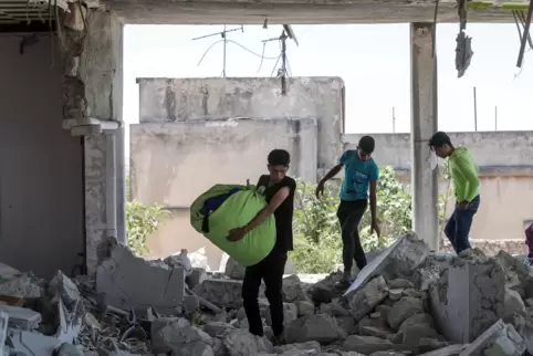 Jugendliche bergen Habseligkeiten aus einem zerstörten Haus, nachdem die syrische Regierung die Stadt Al-Bara in der von Rebelle