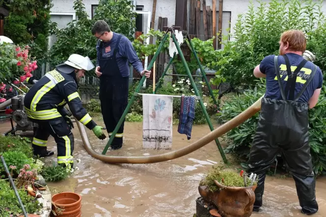 Einsatzkräfte bemühen sich, einen gefluteten Garten in Weisenheim am Sand vom Wasser zu befreien.