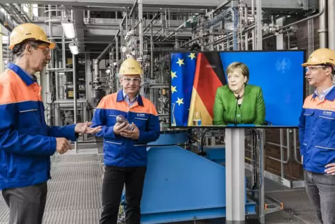 Die BASF-Forscher Detlef Kratz, Dieter Flick und Frederik Scheiff (von links) im Gespräch mit Bundeskanzlerin Angela Merkel.