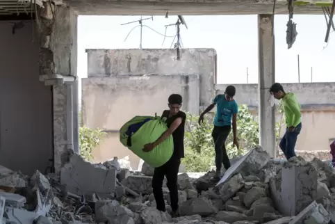 Jugendliche bergen Habseligkeiten aus einem zerstörten Haus in der Region Idlib in Nordsytien, die von Rebellen kontrolliert wir