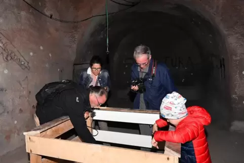 Armin Kupper (links) zeigt den Besuchern die Wassersammelstelle des Bunkers. 