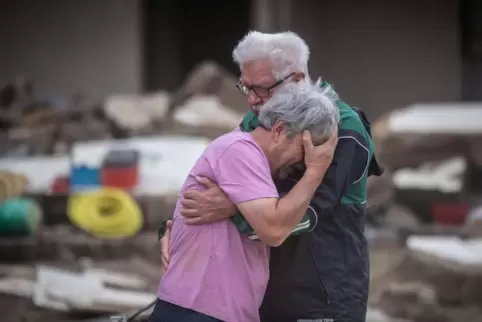 Weinend liegen sich zwei Brüder vor ihrem zerstörten Elternhaus in Altenahr in den Armen.
