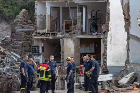 Mayschoß: Feuerwehrleute vor zerstörtem Gebäude. 