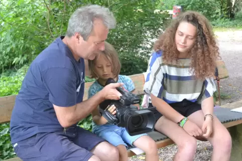 Dreh im Domgarten: Johannes Grehl zeigt zwei Projektteilnehmern, wie die Videokamera funktioniert.