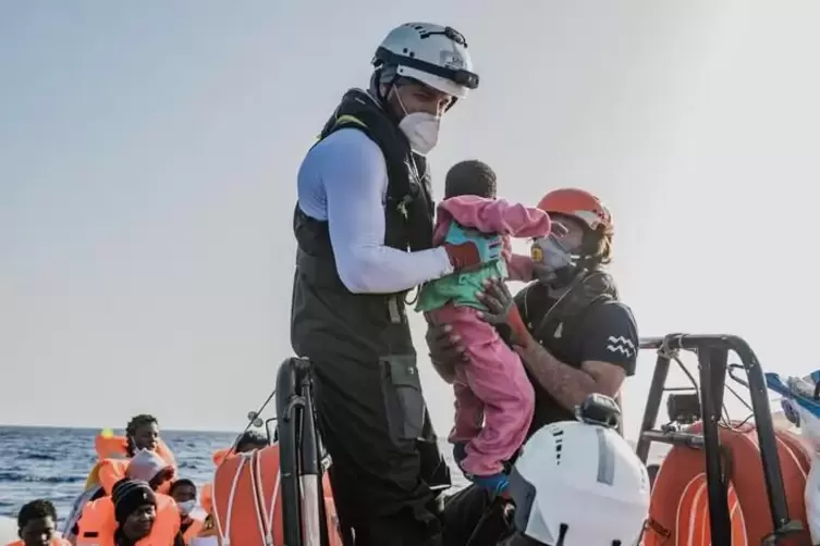 Helfer der „Ocean Viking“ retten ein Kind aus einem Schlauchboot. 