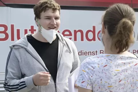 Max Rieger im Gespräch mit Rebekka Sambale. Wie alle in der Schlange am Impfbus, trägt er eine Maske, die er nur fürs Foto kurz 