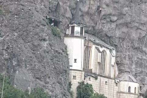 In schwindelnder Höhe müssen die Arbeiter den Fels um die Kirche sichern. 