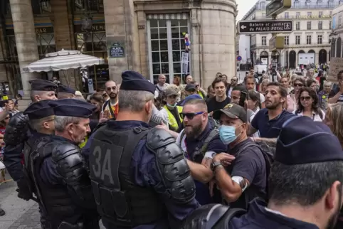Menschen stehen in Paris bei einem Protest gegen den Gesundheitspass Polizisten gegenüber. 