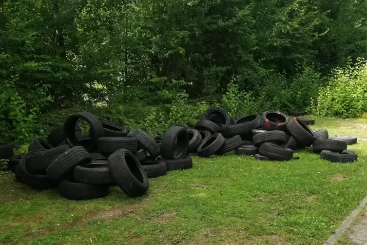 Illegal entsorgt: 60 alte Reifen auf einem Parkplatz. 