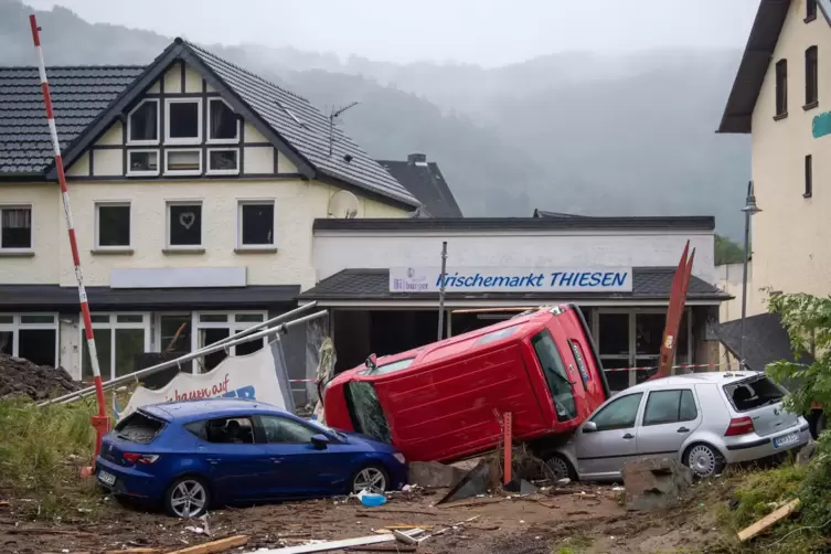 Zerst&ouml;rte Autos liegen am Rande der Ahr vor dem verw&uuml;steten Stadtkern von Schuld.