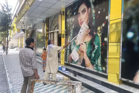  Ein Mitarbeiter eines Schönheitssalons in Kabul übermalt ein großes Foto einer Frau an der Wand, nachdem die Taliban in die afg